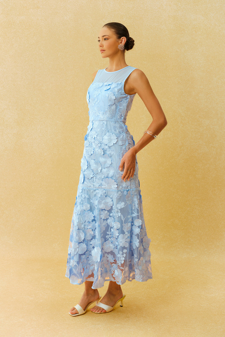 Model trägt das blaue Maxikleid mit Blumenapplikation - KYMA