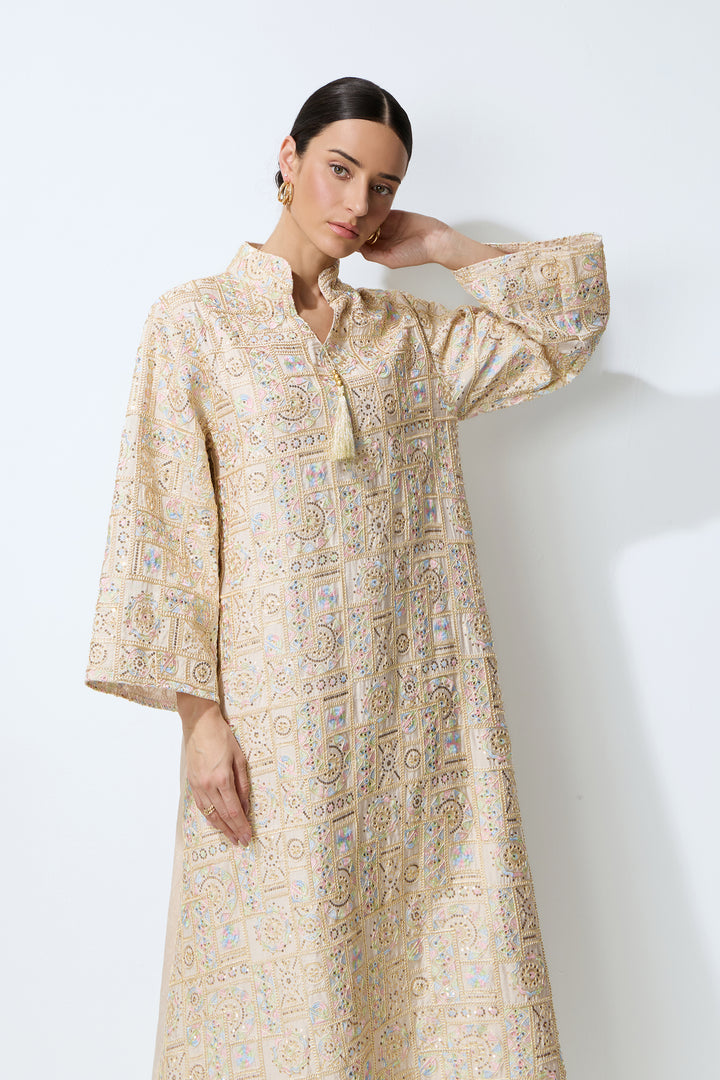 Nahaufnahme der geometrischen Stickerei und Pailletten auf dem apricotfarbenen Kaftan-Maxikleid – KY