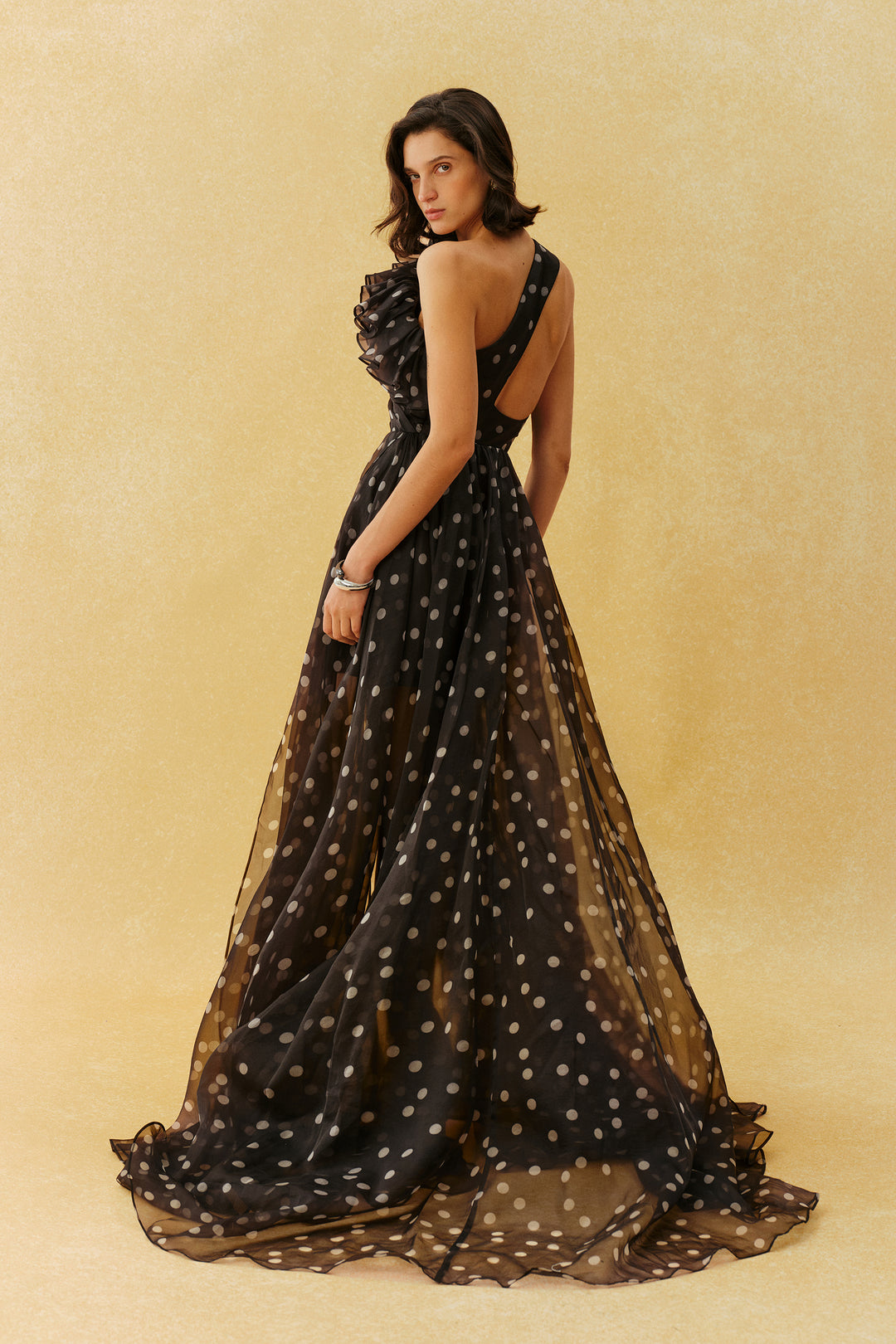 Schwarzes Polka-Dot Maxikleid mit Rüschenkragen und seitlichem Schlitz, das die Figur einer Frau bet