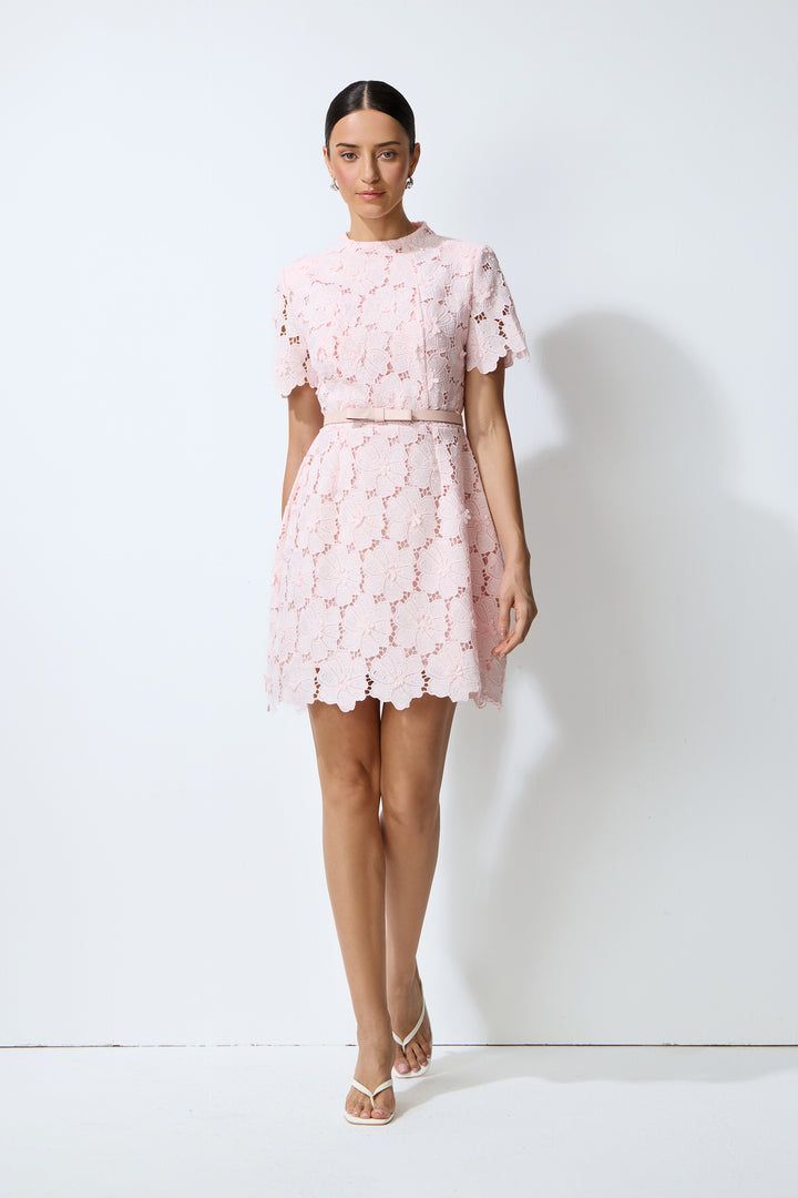 Model trägt das rosa Spitzen-Minikleid mit Stoffgürtel
